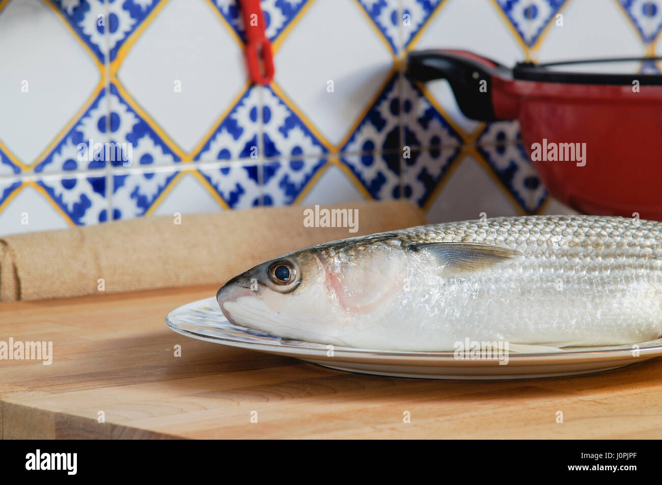 Mullet striped mullet contains omega-3 acids, vitamins and minerals. Mullet lying on plate ready for cooking. Stock Photo