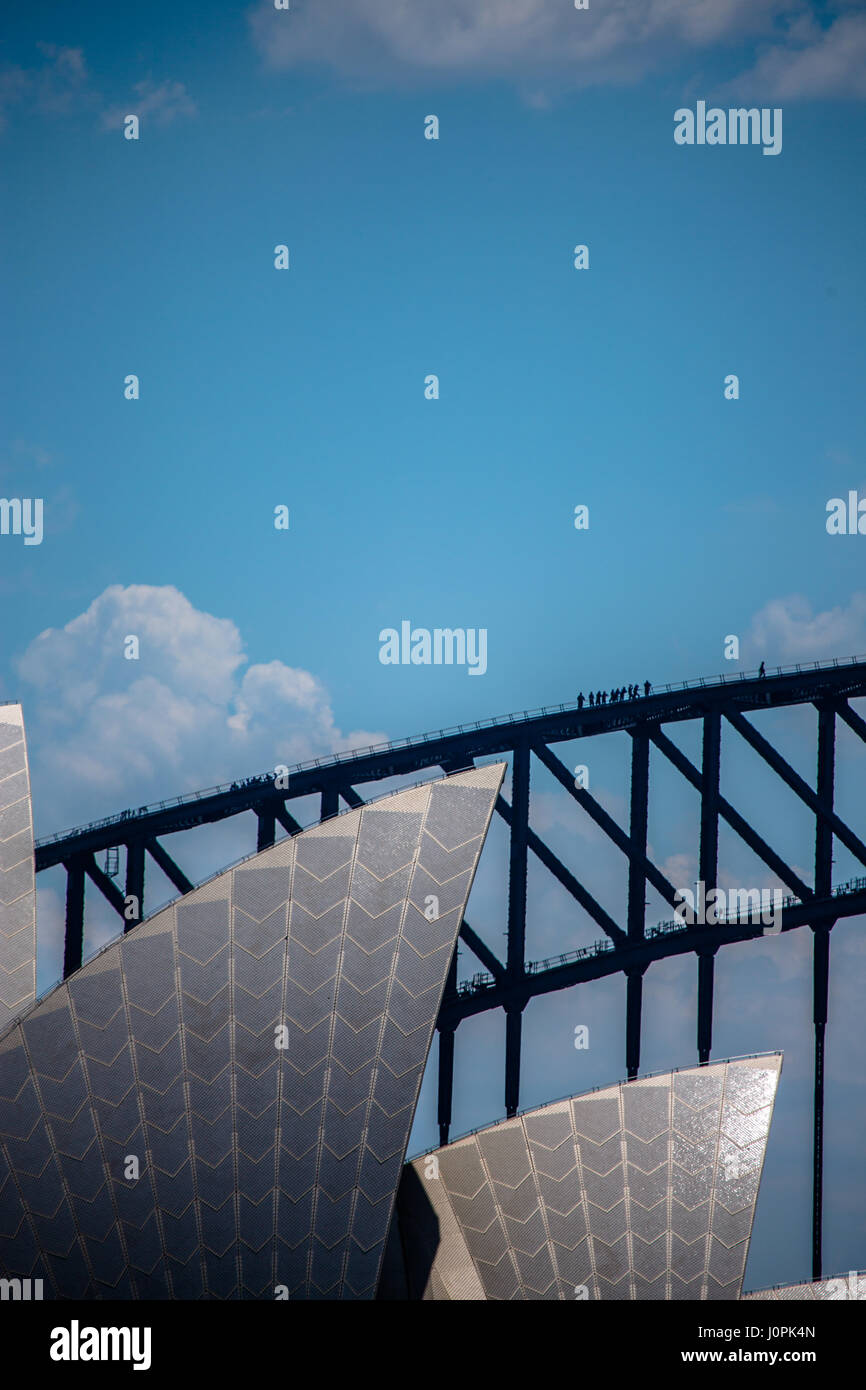 Bridge climbers climb the Sydney Harbour Bridge with the Sydney Opera House in the foreground. Stock Photo