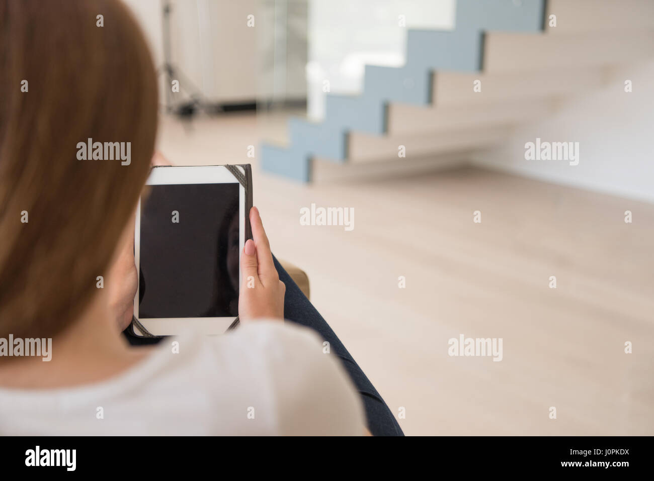 young happy woman sitting on sofa with tablet computer at luxury home ...