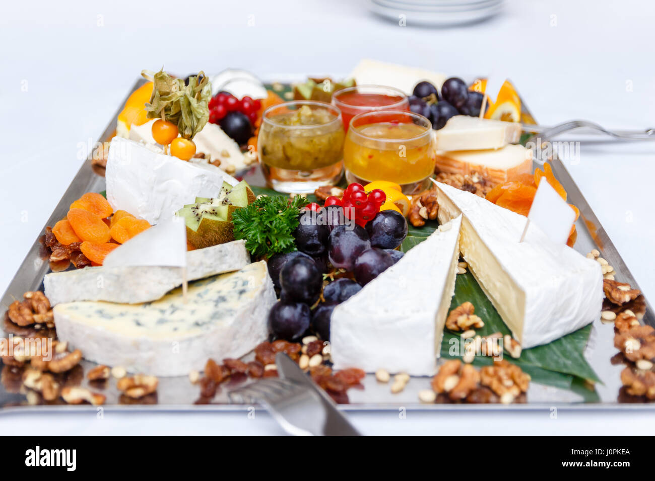 Collection of various delicious types of cheese, grapes and nuts on a light grey table Stock Photo
