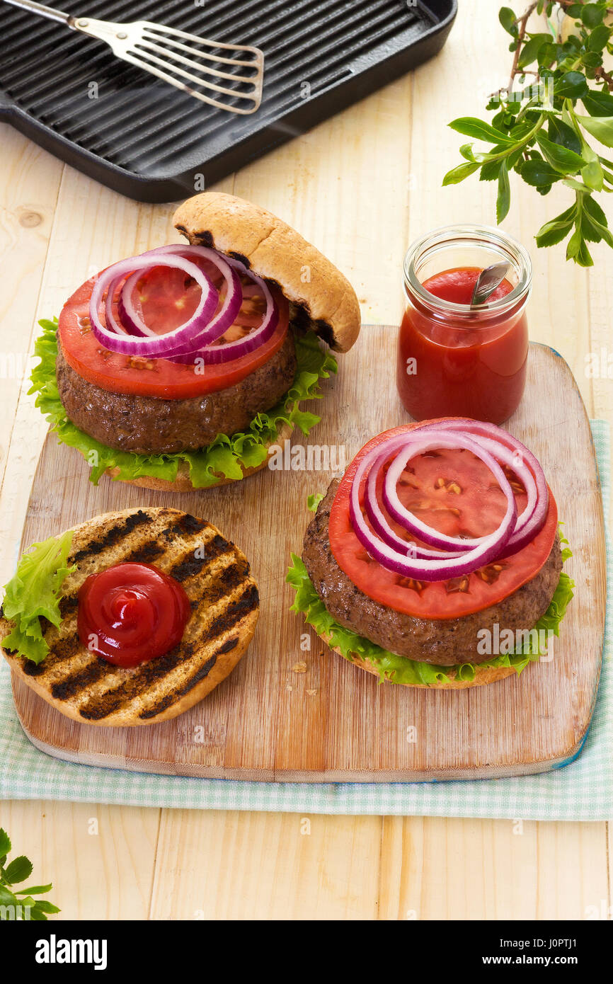 Burger with lettuce tomato red onion on grilled buns with ketchup Stock