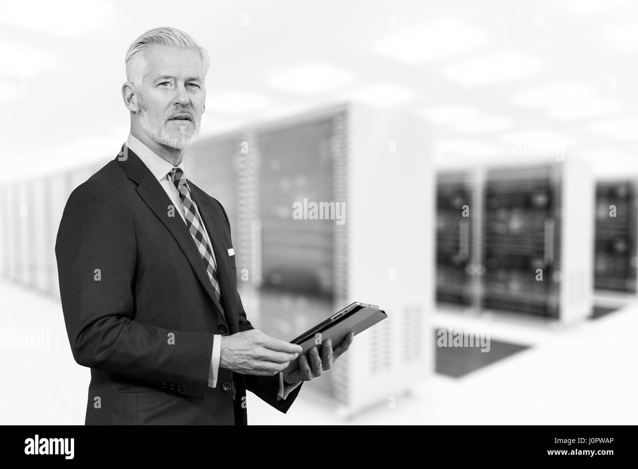 Portrait of senior businessman in big rack server room Stock Photo
