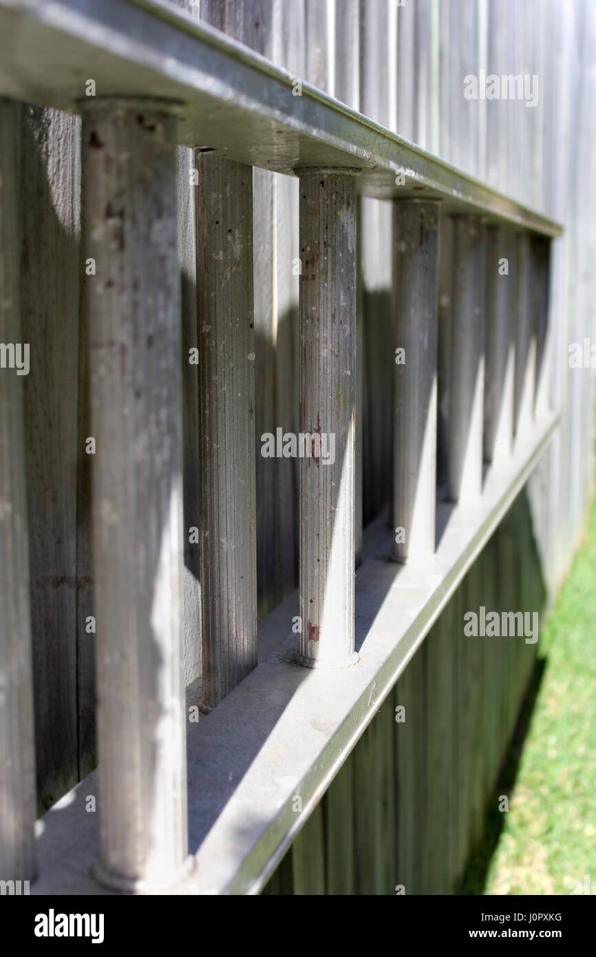 Macro of Aluminum ladder hanging on backyard fence with soft focus background Stock Photo