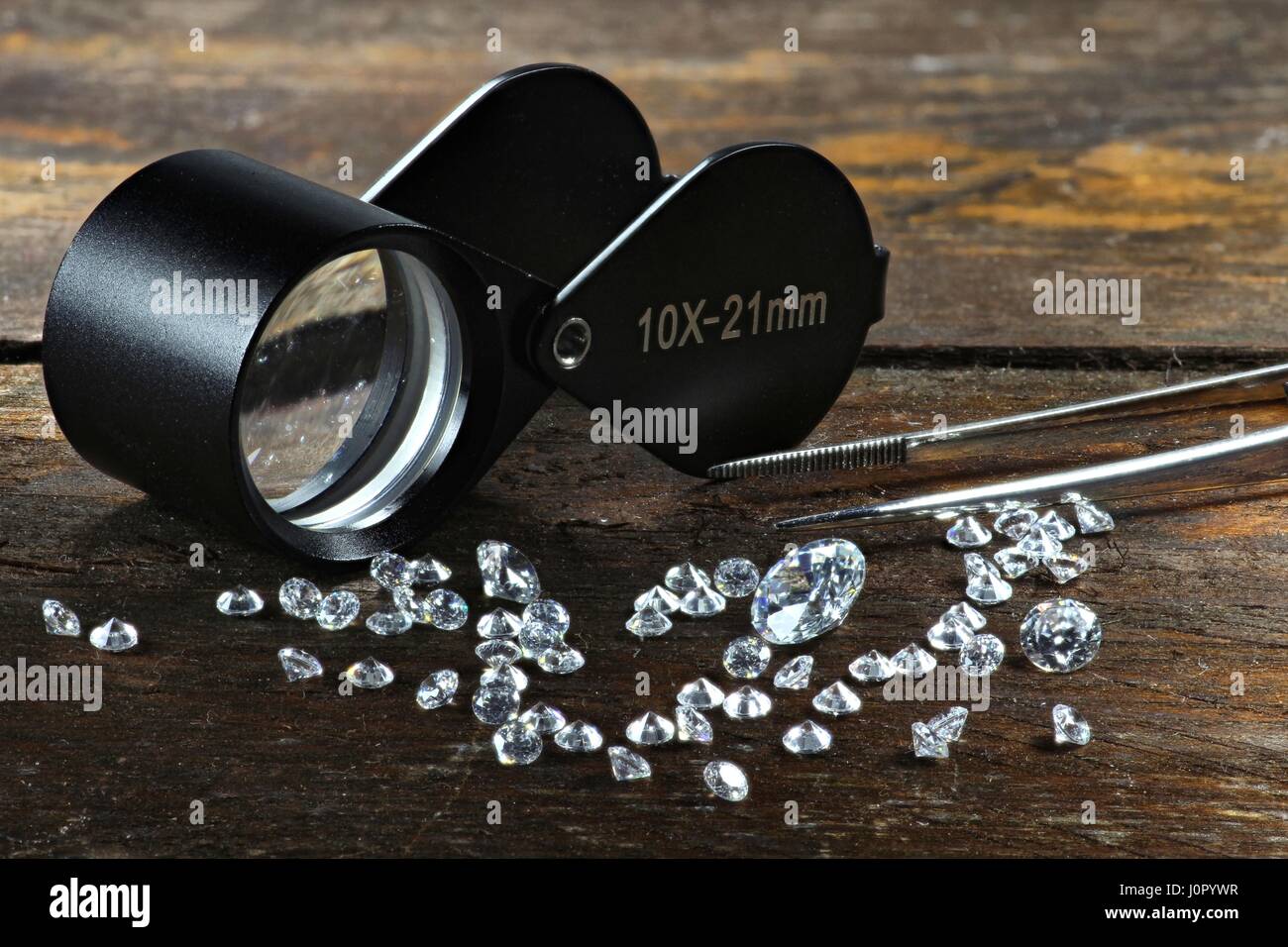 cut diamonds with folding magnifier on wooden background Stock Photo