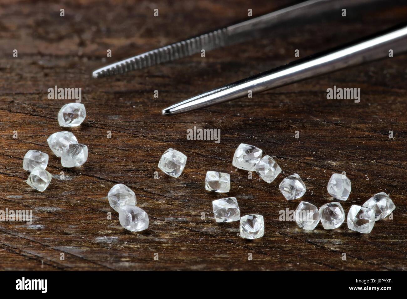 rough diamonds with tweezers on wooden background Stock Photo