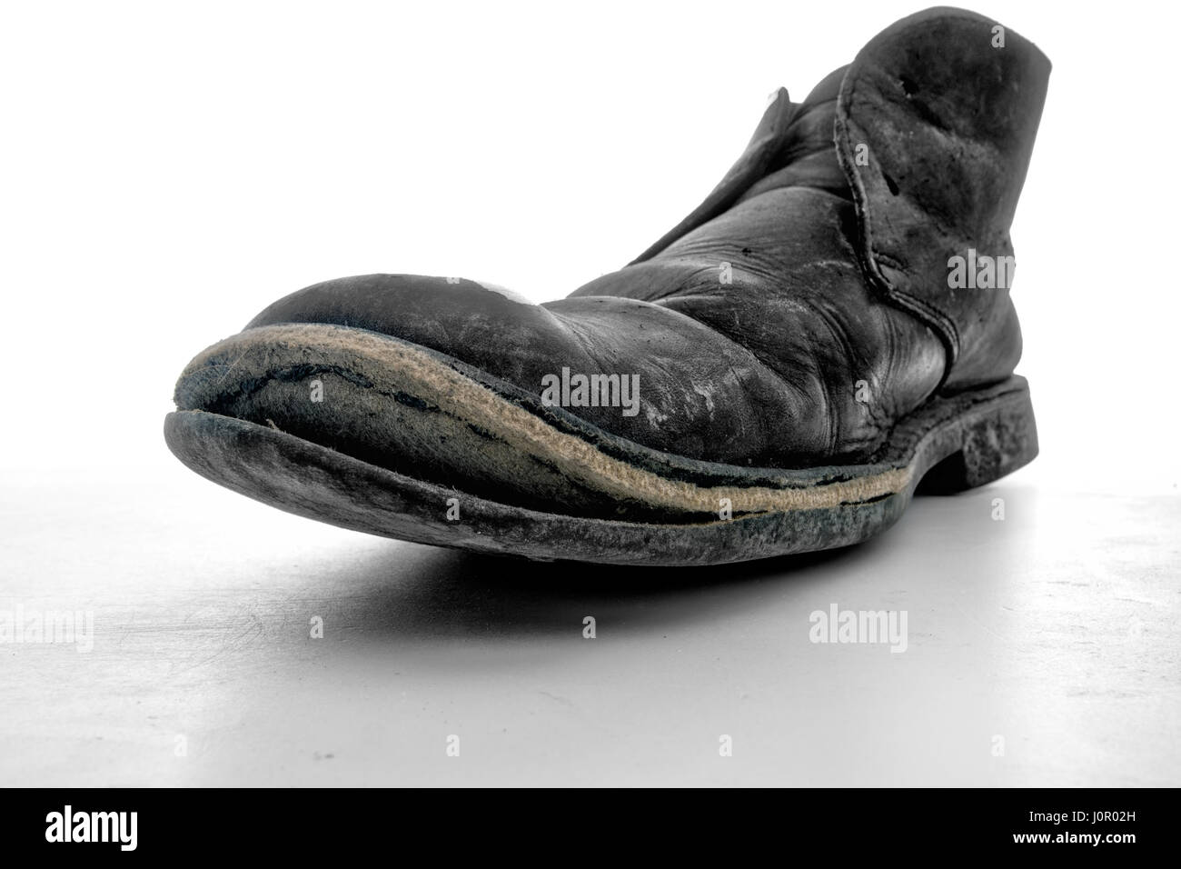 Man's old work boot 'laughing' ie sole split from shoe.Wide angle view for effect. Shoe mender wanted! Stock Photo