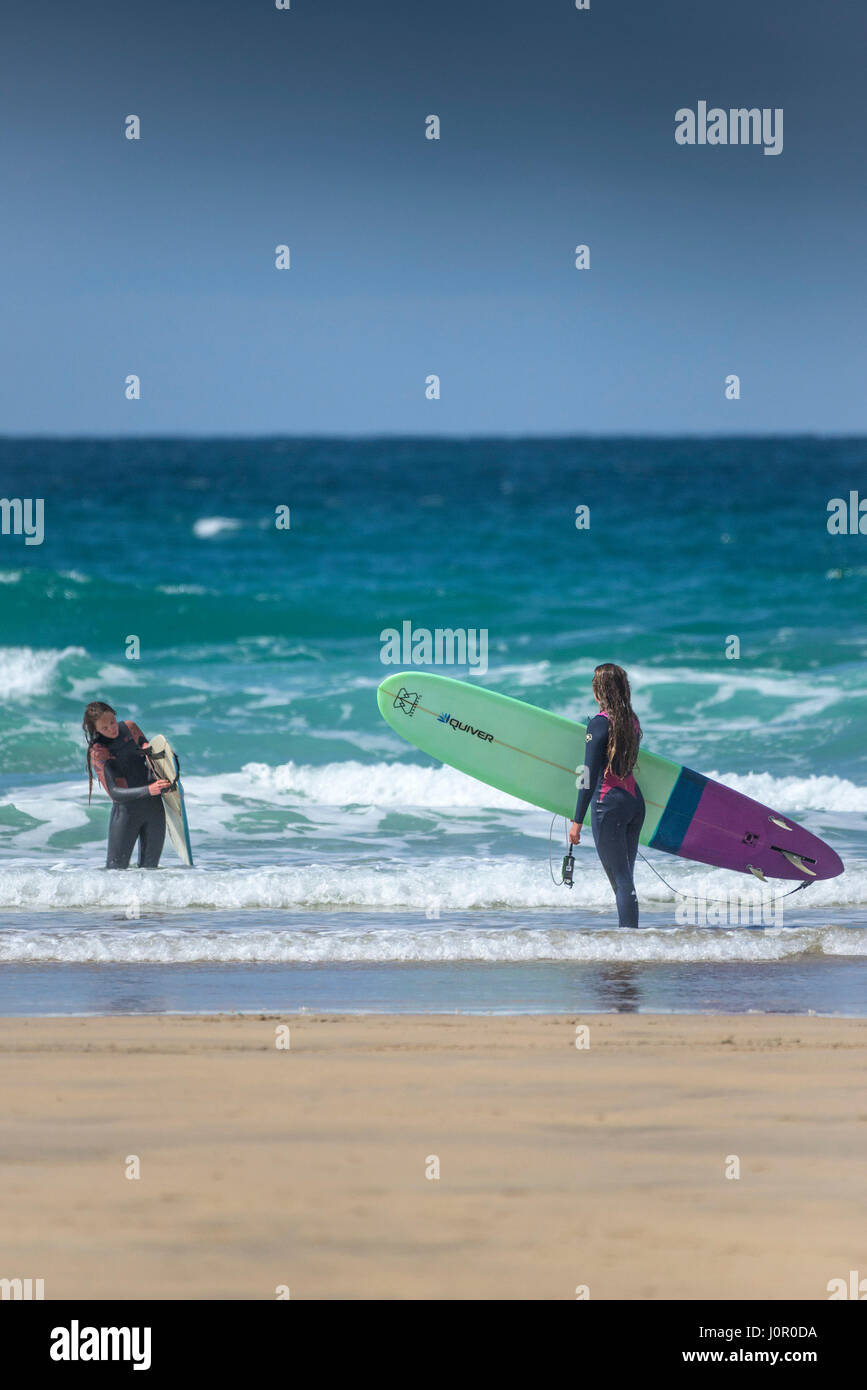 UK surfers Fistral Newquay Female surfers Leaving the sea Walking out of the sea Carrying surfboard Surfing Watersport Seaside Tourism Stock Photo