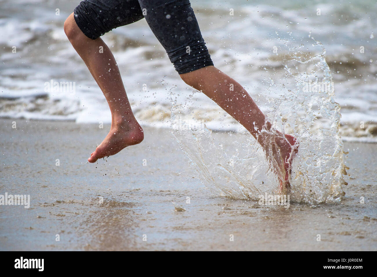 Fistral Newquay Person running along shoreline Splash Splashing Runner Spray Water Barefoot Energy Energetic Seaside Tourism Beach Holiday Stock Photo