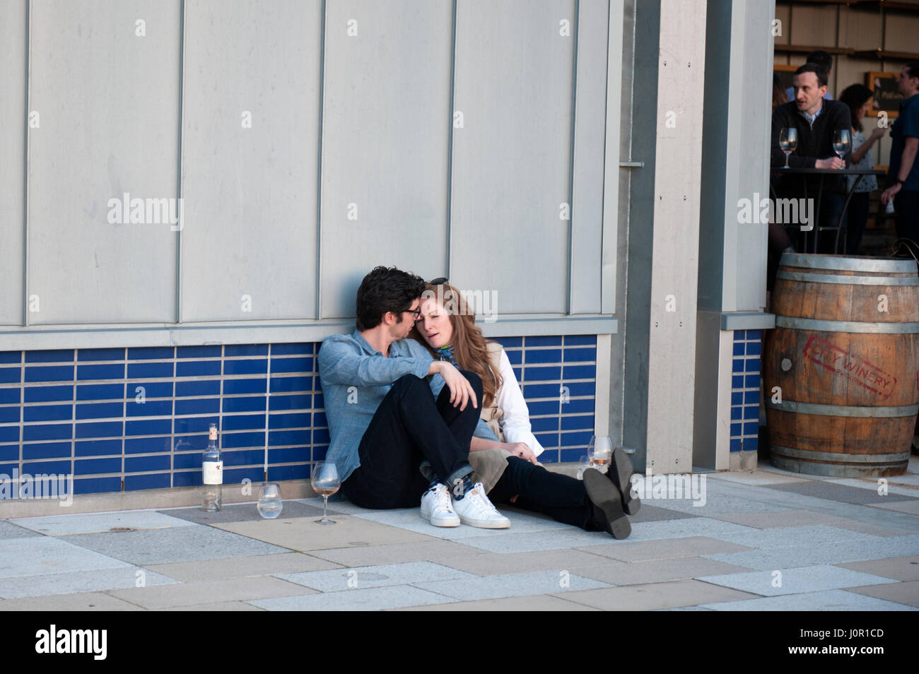 A couple sits on the pavement outside City Vineyard, a restaurant on Pier 26 in the Tribeca section of Hudson River Park. April 14, 2017 Stock Photo