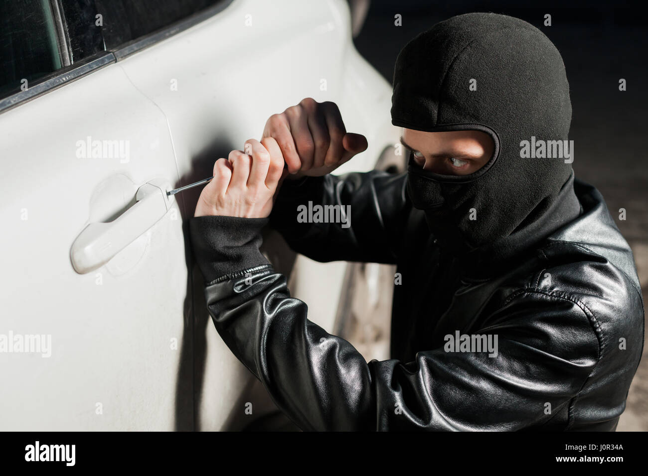 Male Thief Hands Trying To Open Car Door With Screwdriver