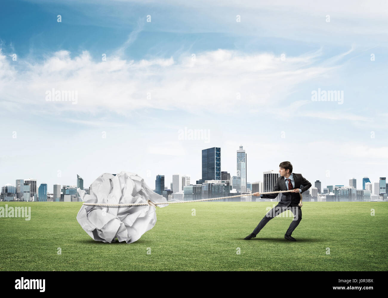 Man pulling with effort big crumpled ball of paper as creativity sign