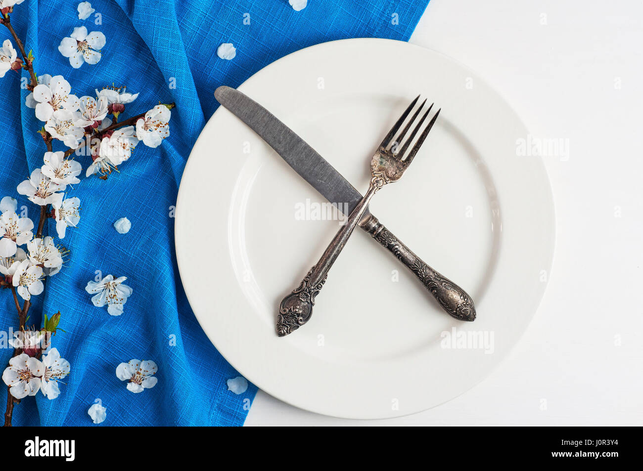 Crossed knife and fork on an empty white plate, top view Stock Photo