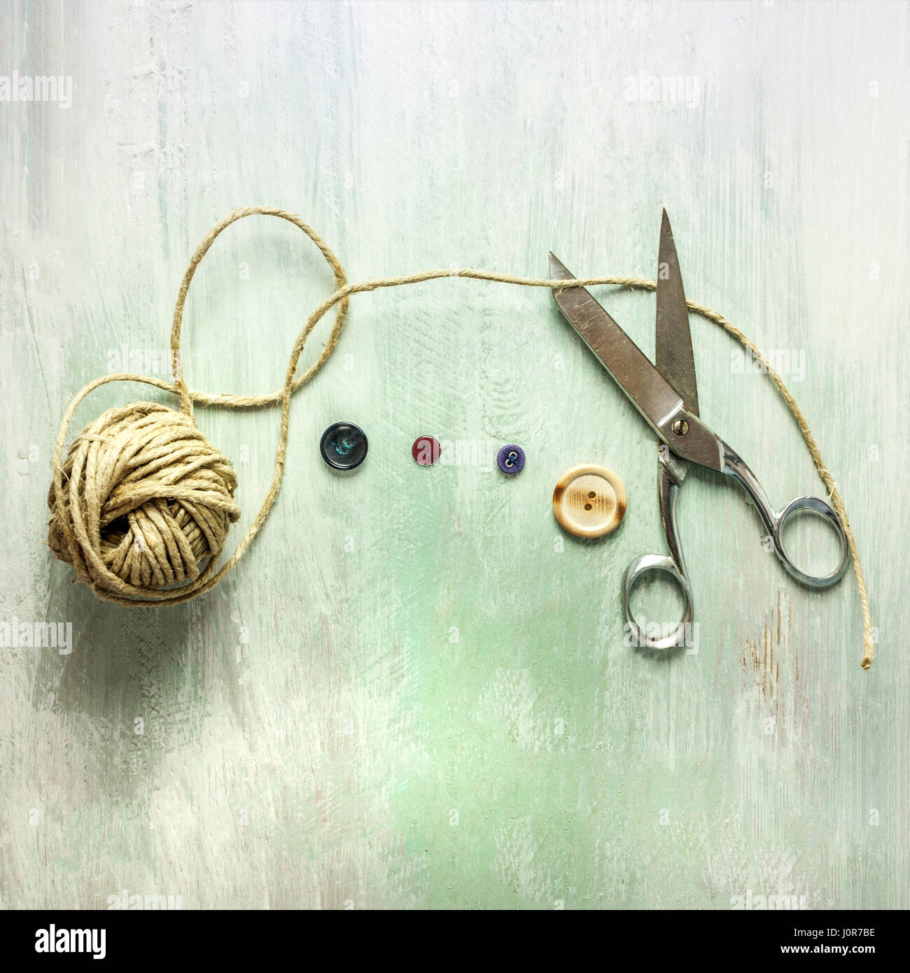 A square photo of vintage scissors with a roll of twine and buttons ...