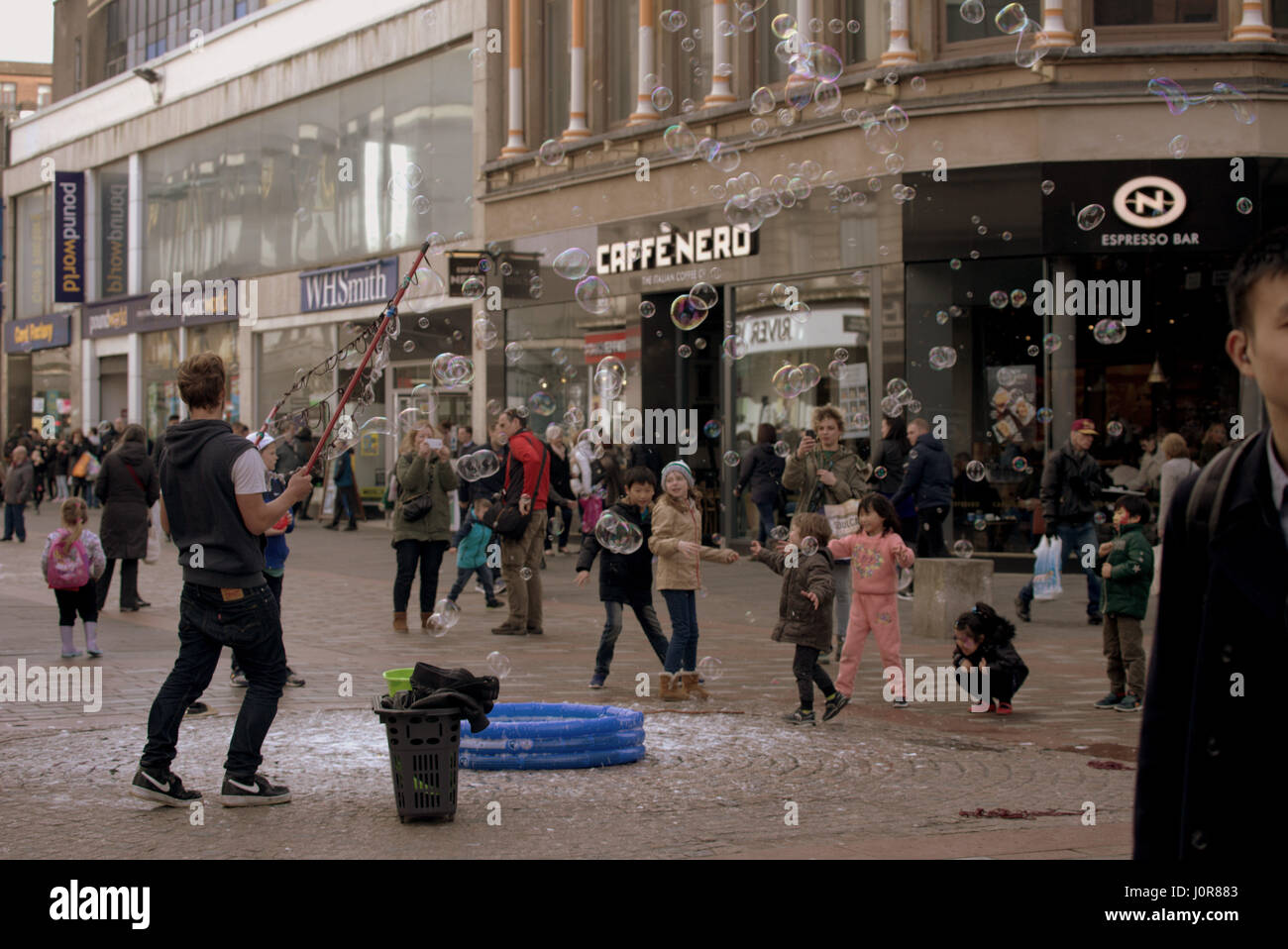 street entertainer blowing bubbles to entertain children on Argyle street Glasgow Scotland Stock Photo