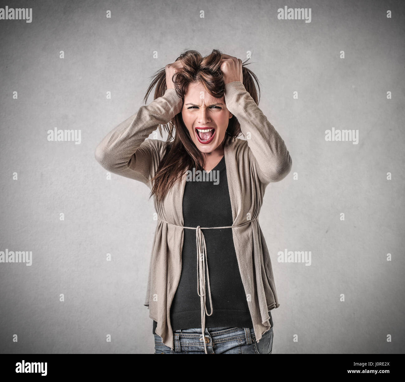 Mad brunette woman yelling and holding her head Stock Photo