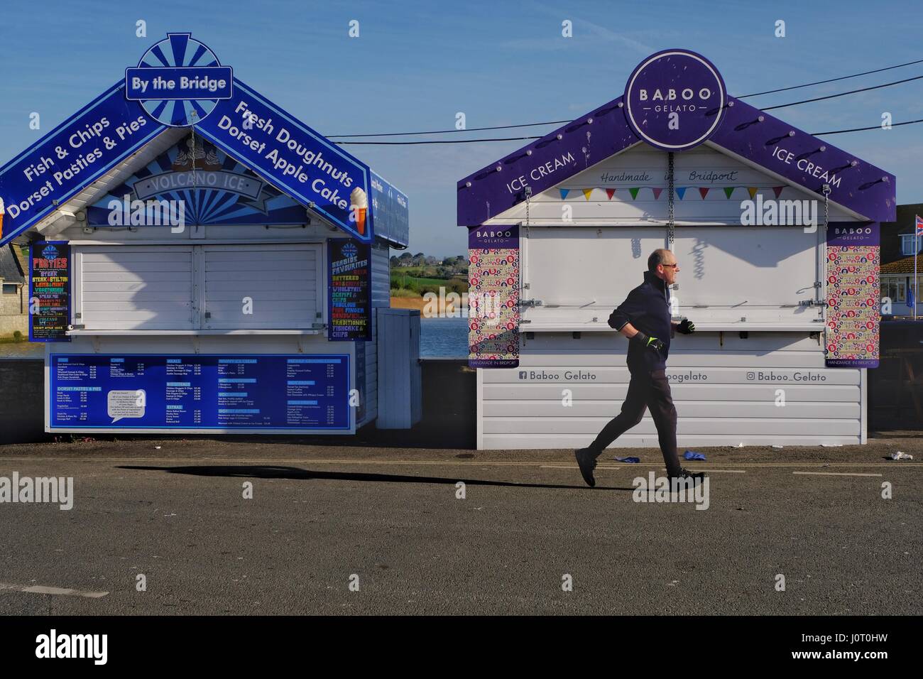 West Bay,  Dorset, UK. 16 April 2017. An early morning runner enjoys the sunshine at West Bay before the Easter Sunday crowds arrive. Credit: Tom Corban/Alamy Live News Stock Photo