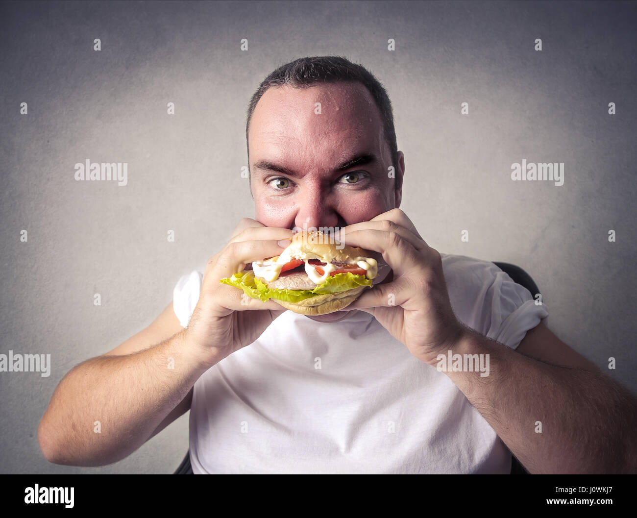 Obese man eating hamburger Stock Photo