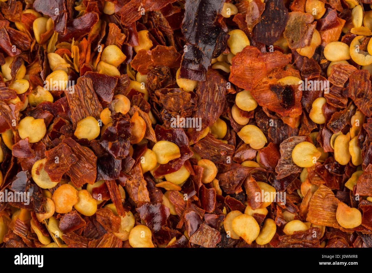The pile of a crushed red pepper, dried chili flakes and seeds as a background Stock Photo Alamy