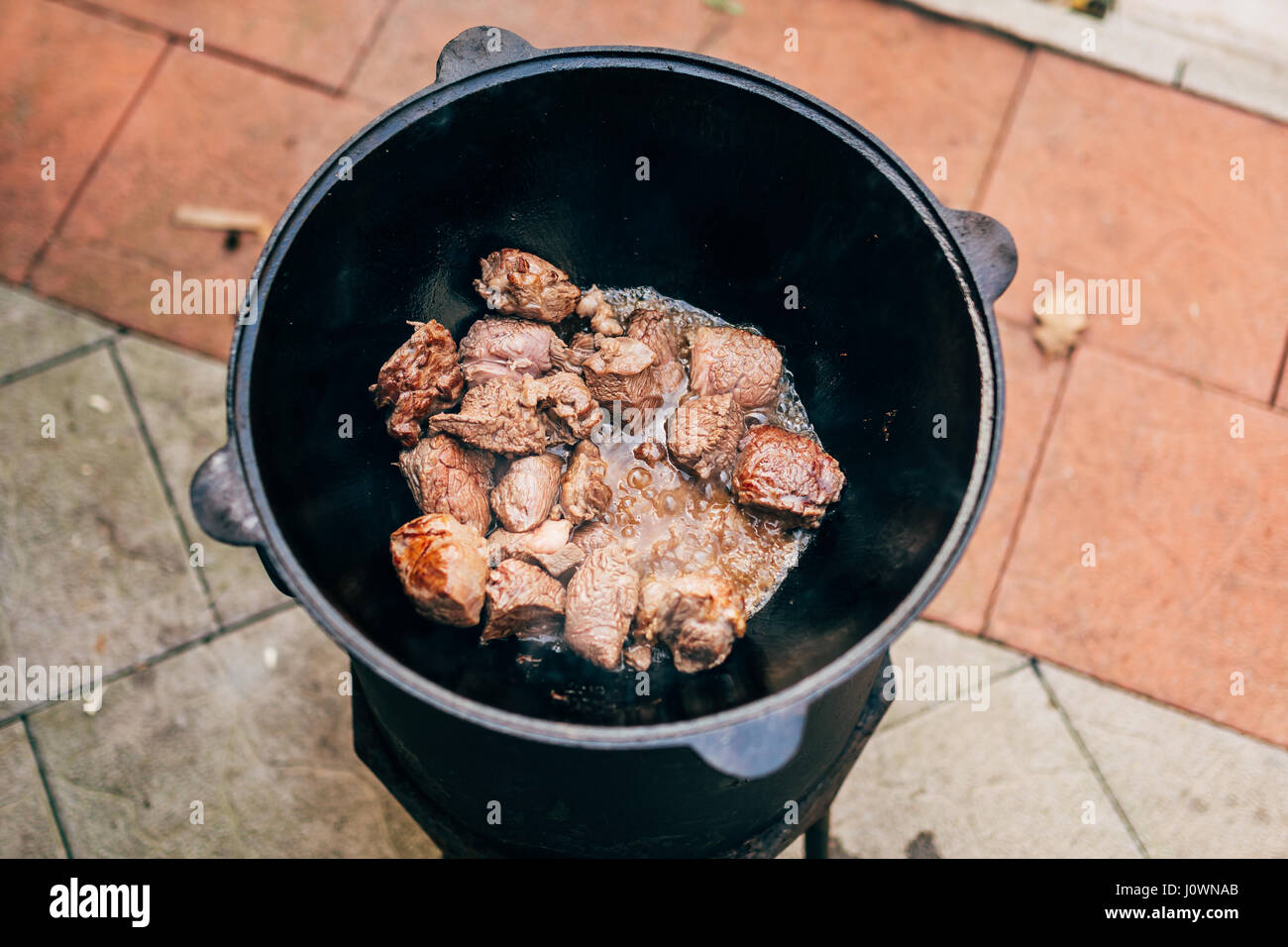 Cooking plov in the cauldron. Only the meat in the cauldron. Field
