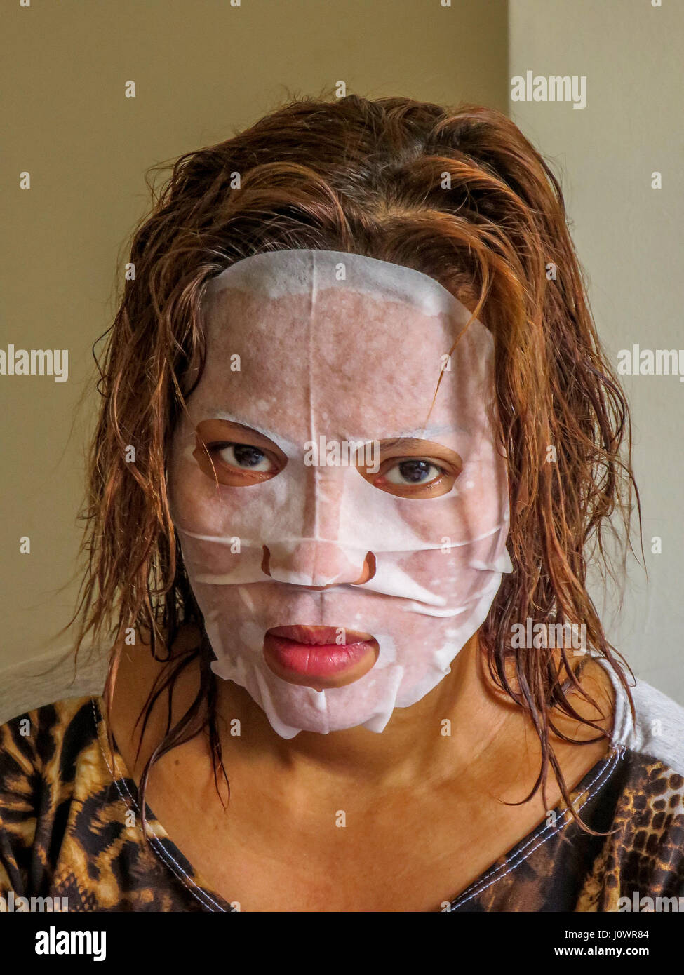 an unhappy Asian woman wears a facial skin complexion mask. Stock Photo