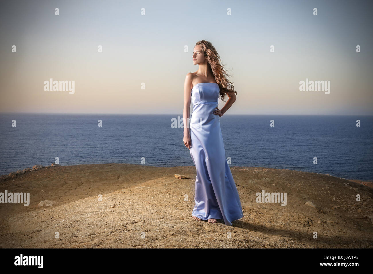 Woman in blue dress posing on the beach Stock Photo - Alamy