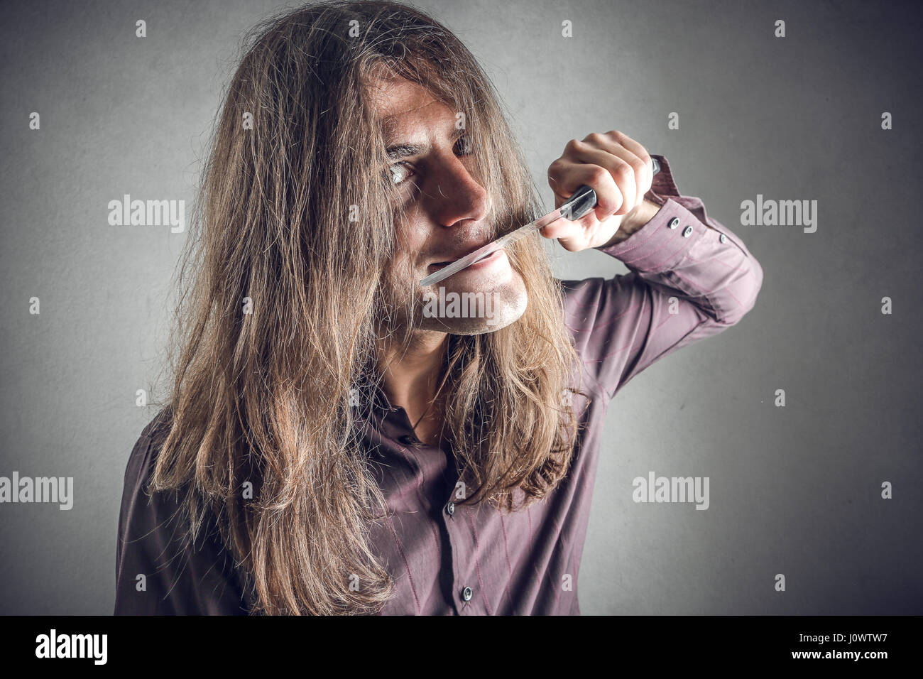 Crazy man licking knife Stock Photo