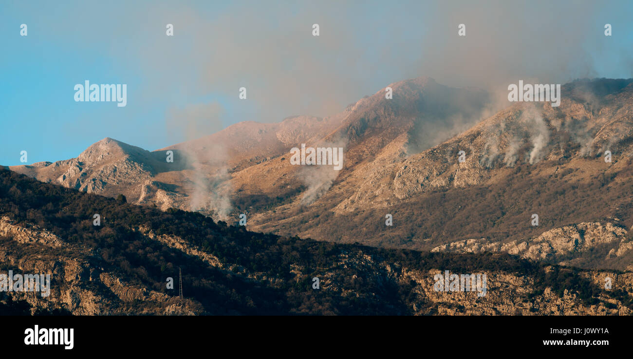 Fire in the mountains in the afternoon. Smoke over the mountains Stock Photo