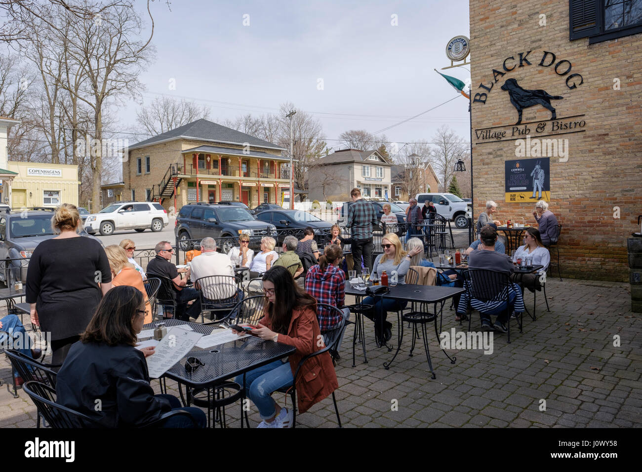 Customers sitting on tables on the outside patio at Black Dog Village Pub & Bistro, a bar, pub, restaurant in the Village of Bayfield, Ontario. Stock Photo
