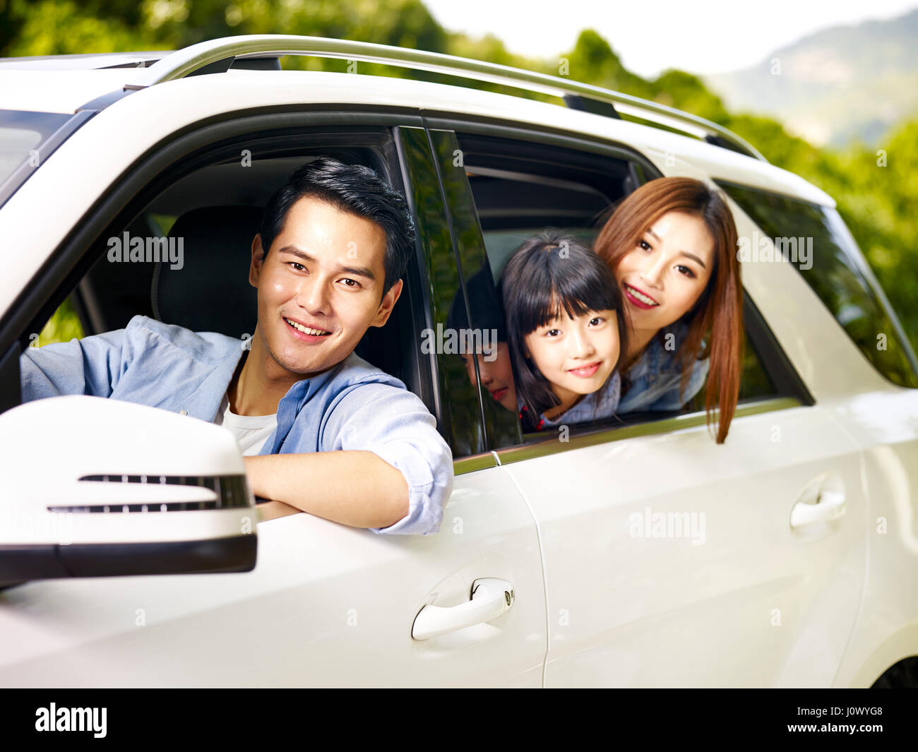 happy asian family traveling by car looking at camera smiling. Stock Photo