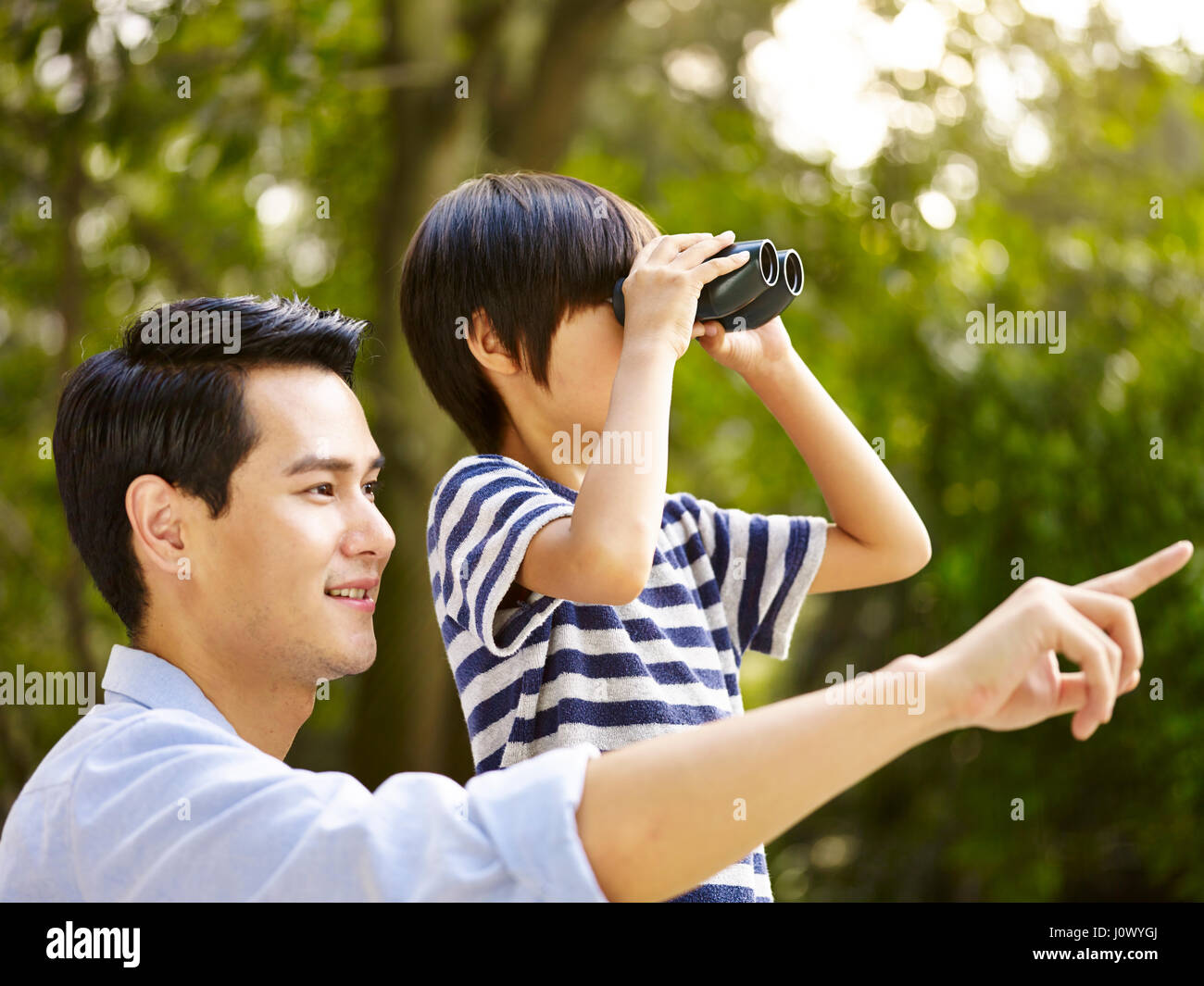 asian father and son using binoculars in park Stock Photo