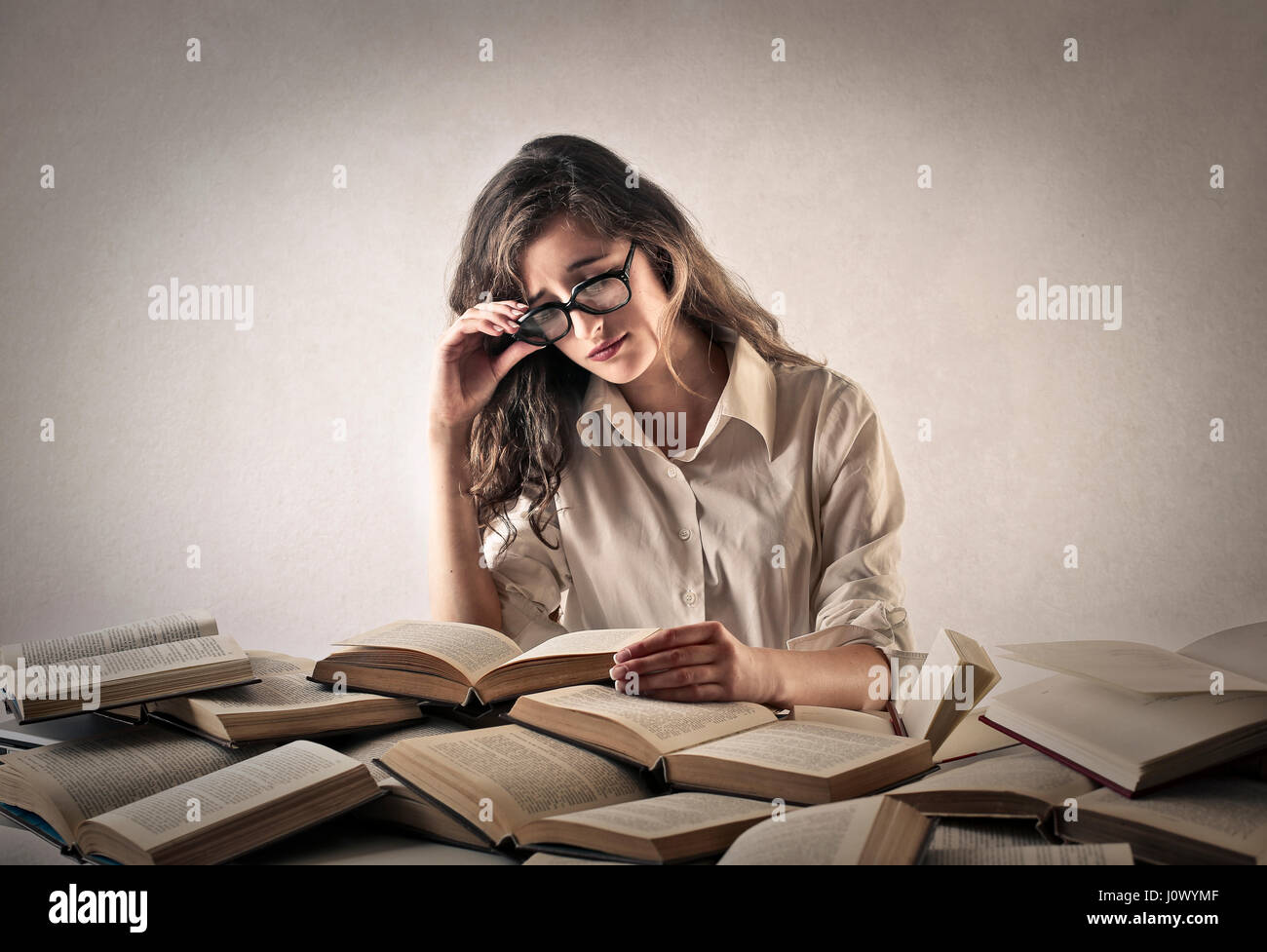 Woman studying from multiple books Stock Photo - Alamy