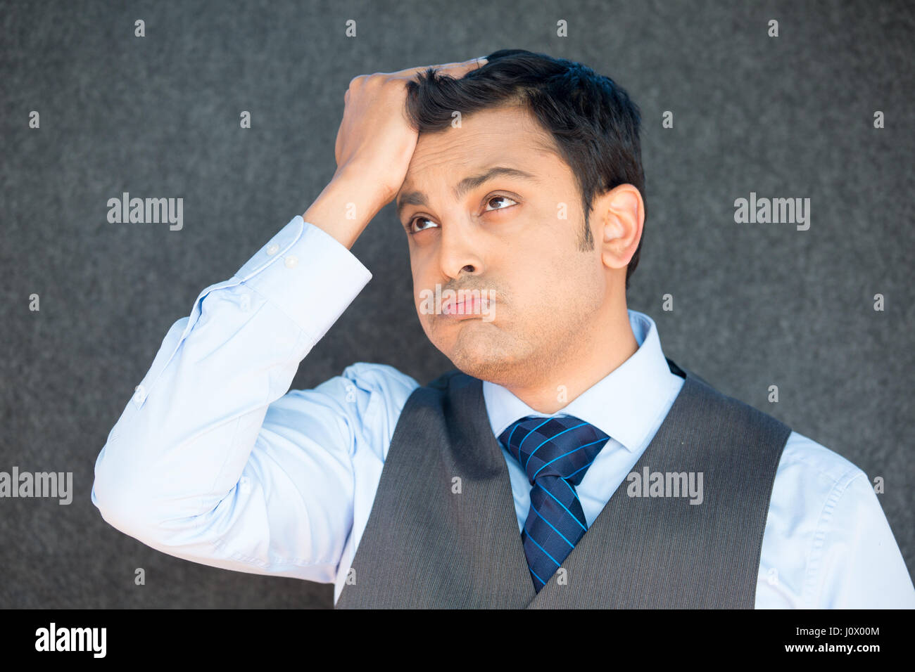 Closeup portrait, stressed young business man with vest and tie, hand on head uh oh, with bad headache, isolated gray black. Negative human emotion fa Stock Photo