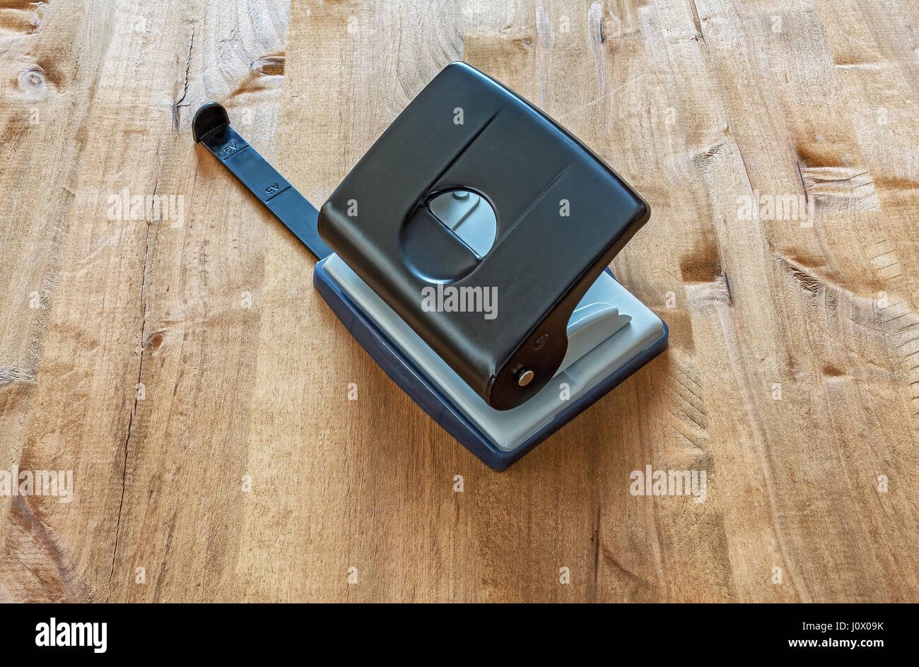 On a wooden table, a hole punch for punching holes in a paper Stock