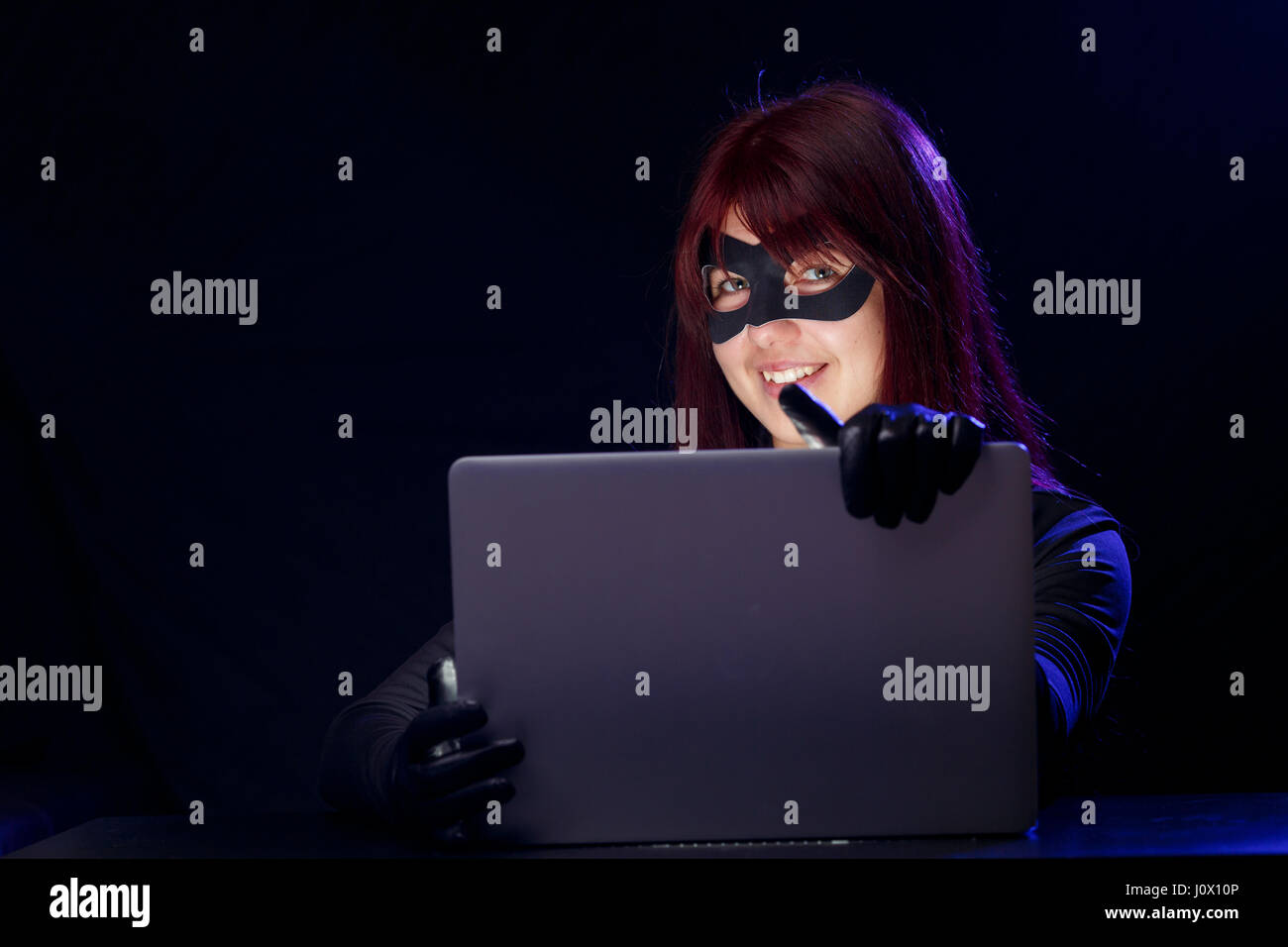 Thief in mask holds laptop Stock Photo - Alamy