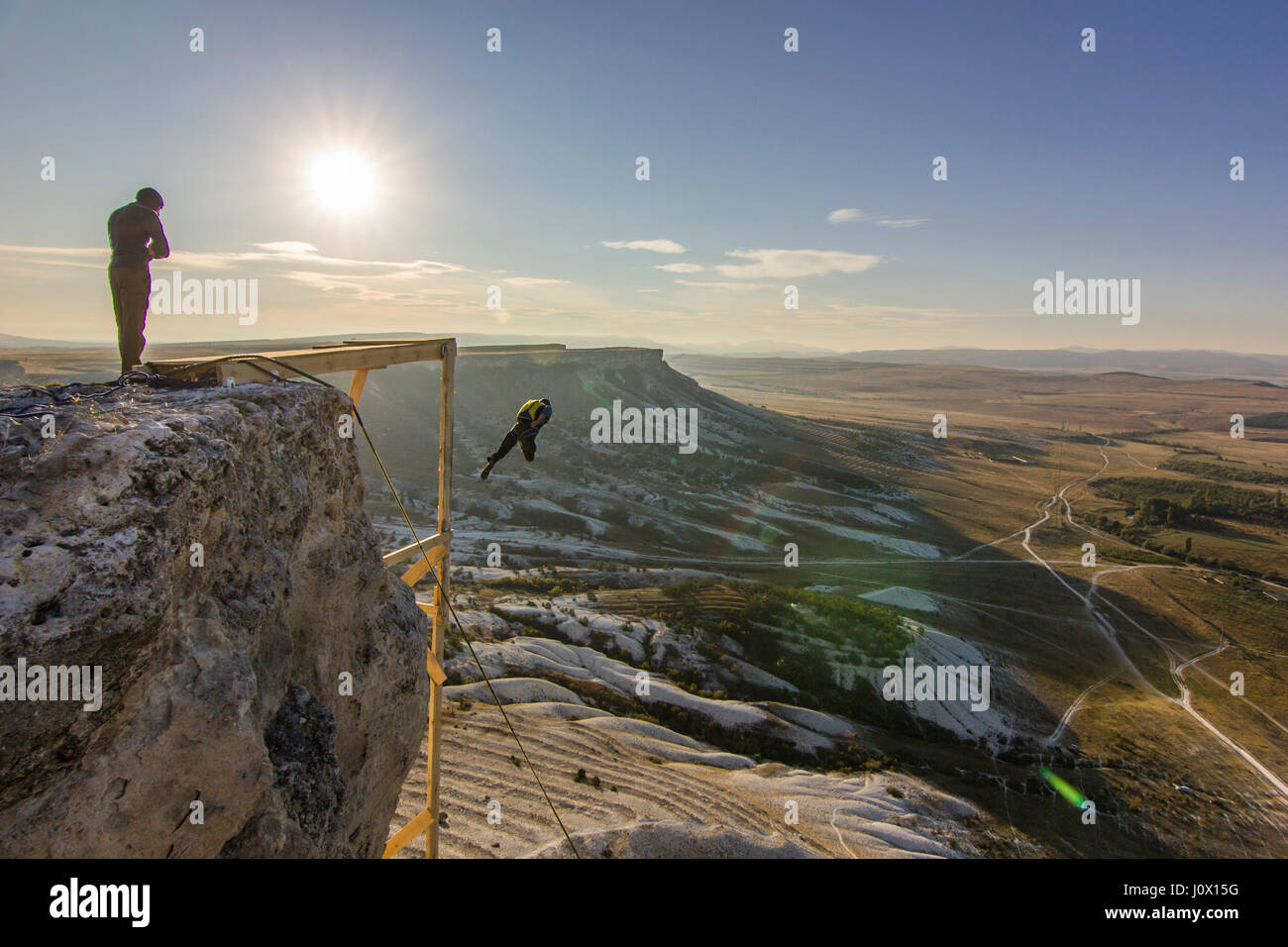 base-jumper prepears to jump from the cliff at sunrise in the mountains Stock Photo