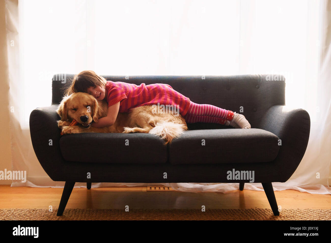 Girl lying on sofa with her golden retriever dog Stock Photo - Alamy
