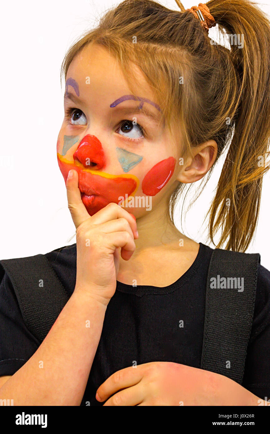 Girl with clown face paint and finger on her lips Stock Photo