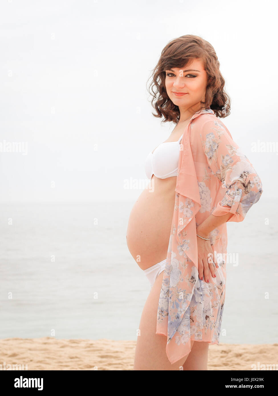 Pregnant woman Standing on beach Stock Photo