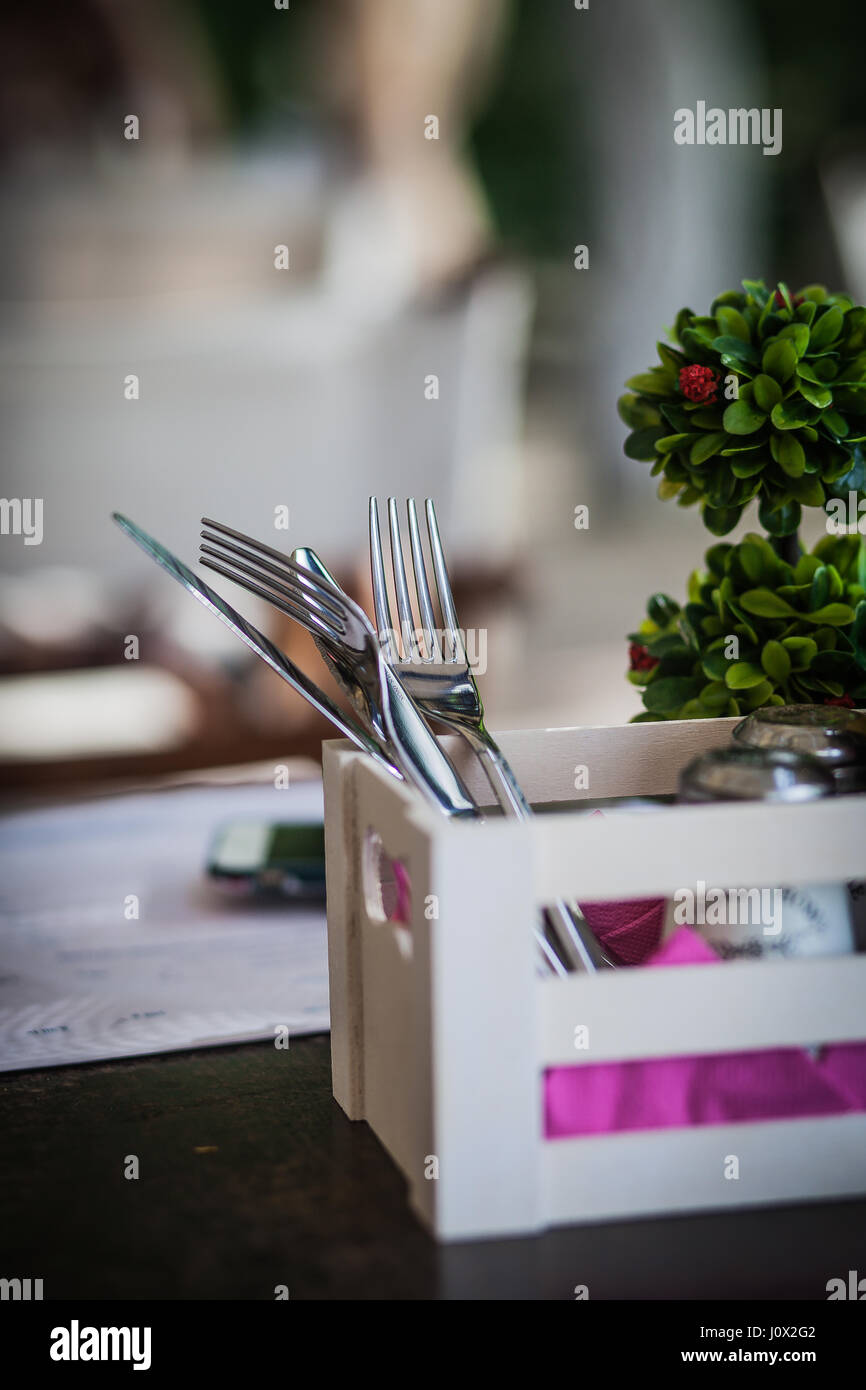 Knives and forks in wooden box on table in restaurant Stock Photo