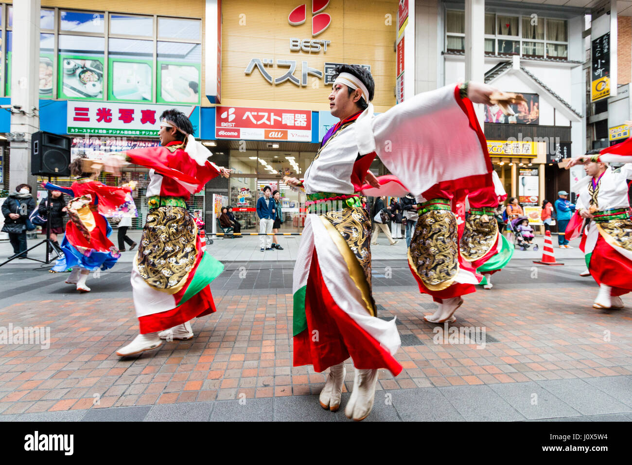 Hinokuni Yosakoi Dance Festival. Male team dressed in red and white yukata with green sash and long swirling sleeves, dancing in shopping mall. Stock Photo