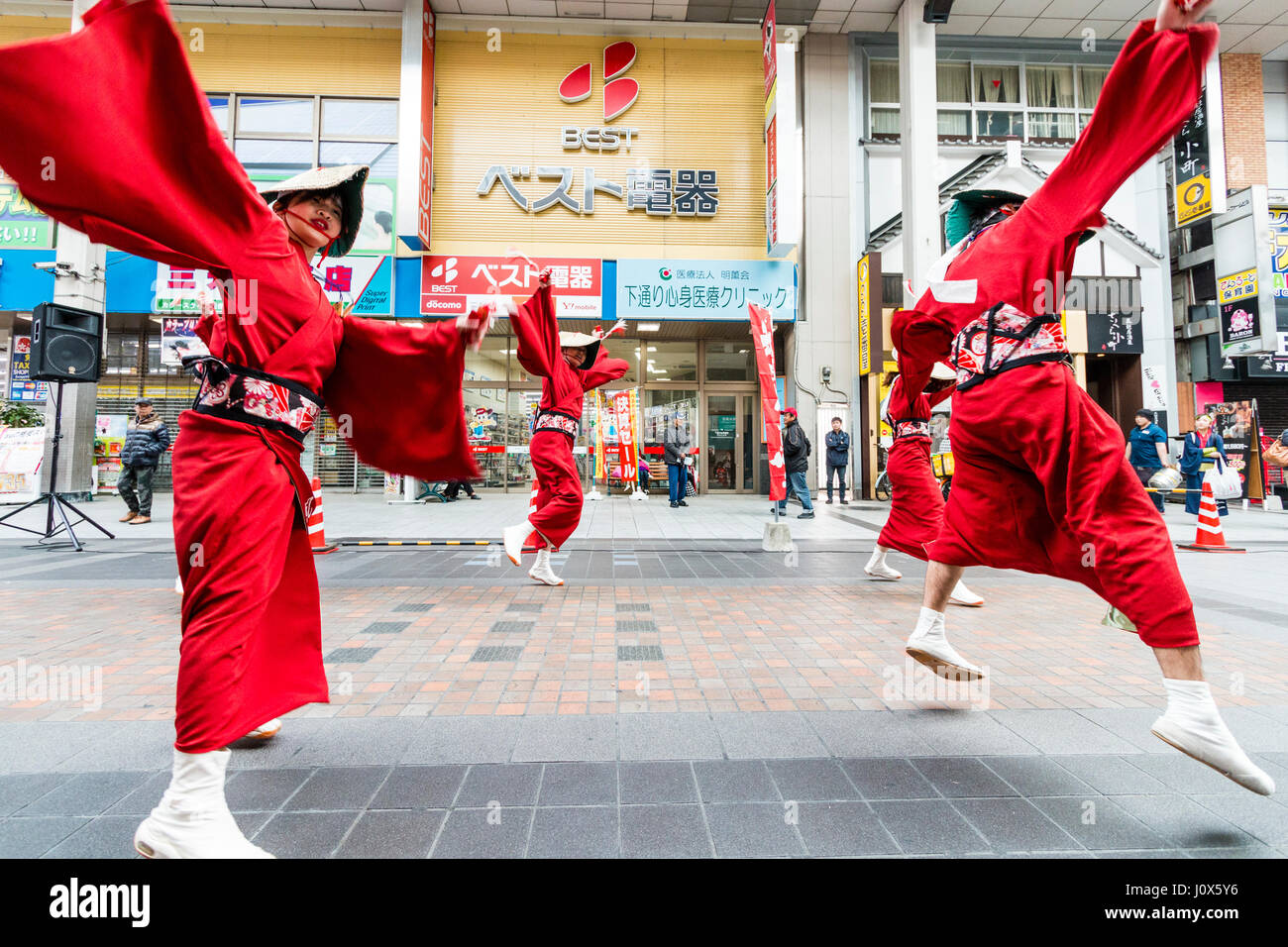 Hinokuni Yosakoi Dance Festival. Team dressed in red farmer costumes with straw hat, dancing in shopping mall. Low angle wide view. Stock Photo