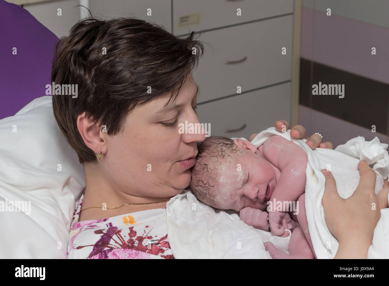 Happy mature woman, mother, with newborn baby immediately after delivery. Stock Photo