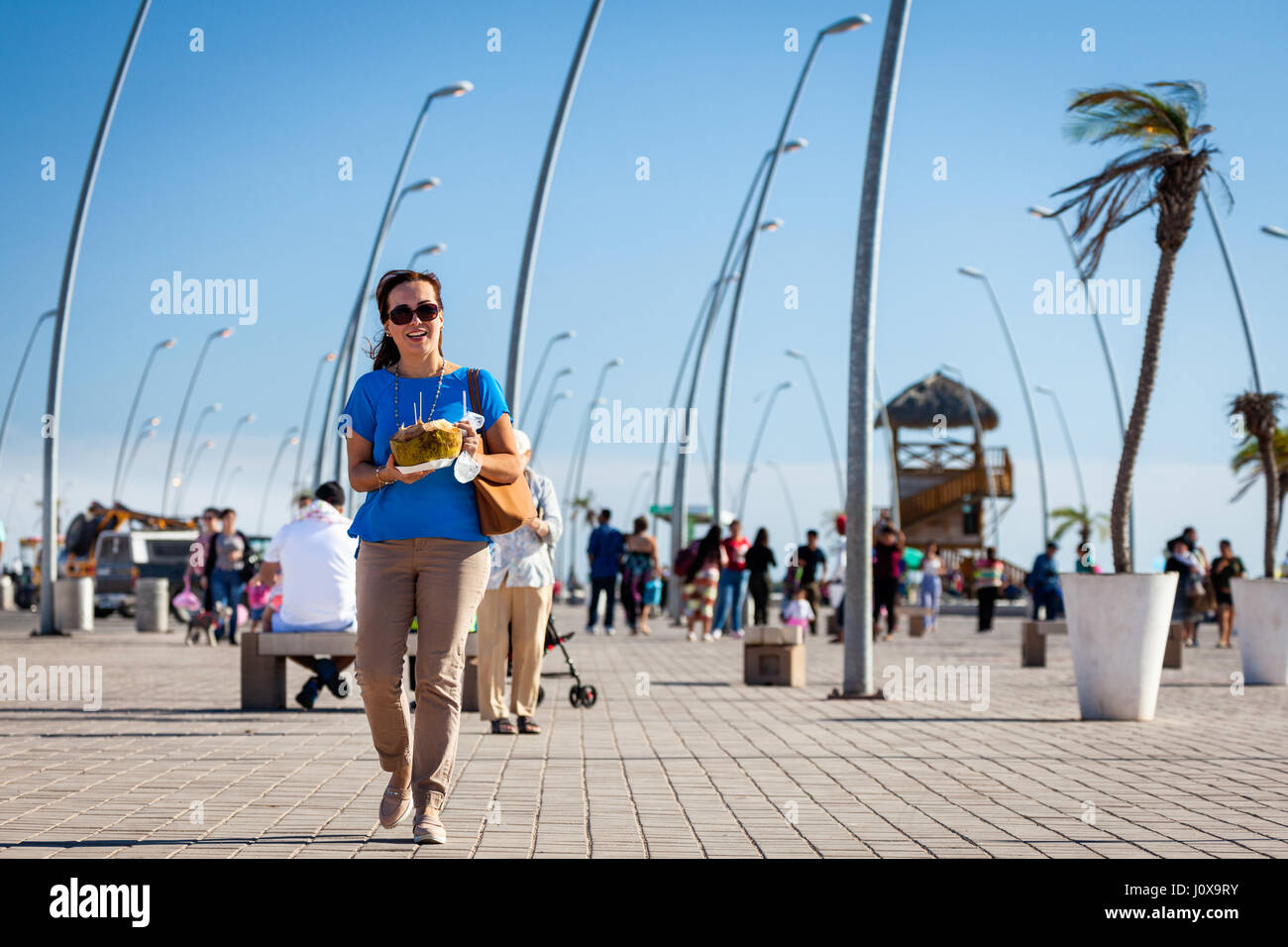 Woman with a fresh coconut walks along the Altata boardwalk near Culiacan, Mexico. Stock Photo