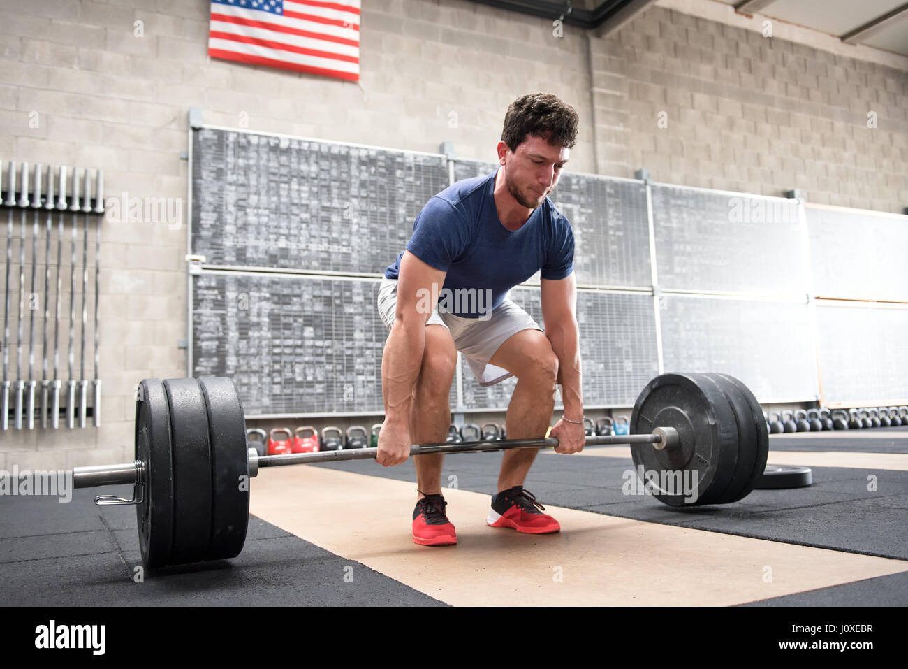 Athlete starting a deadlift in a crossfit gym in which he lifts a heavy