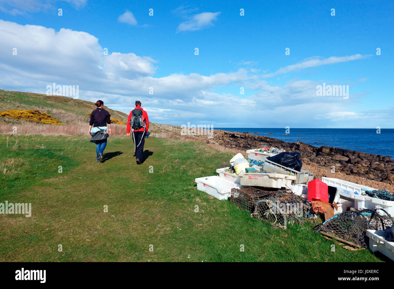 Walkers pass collected marine debris from a recent beach clean up on