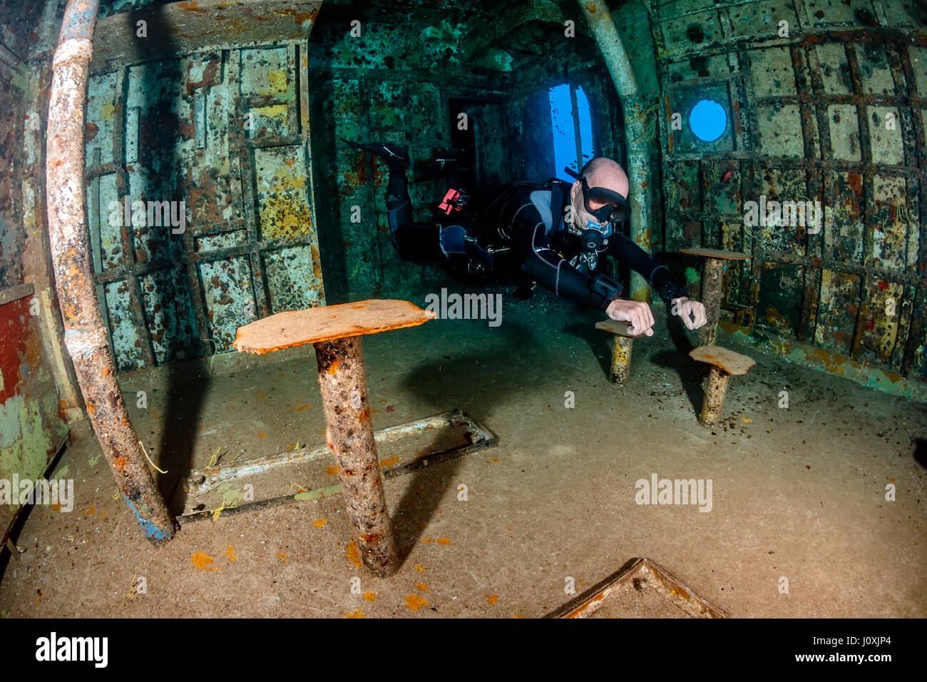 SCUBA diver in sidemount configuration exploring the cafeteria of an underwater shipwreck Stock Photo