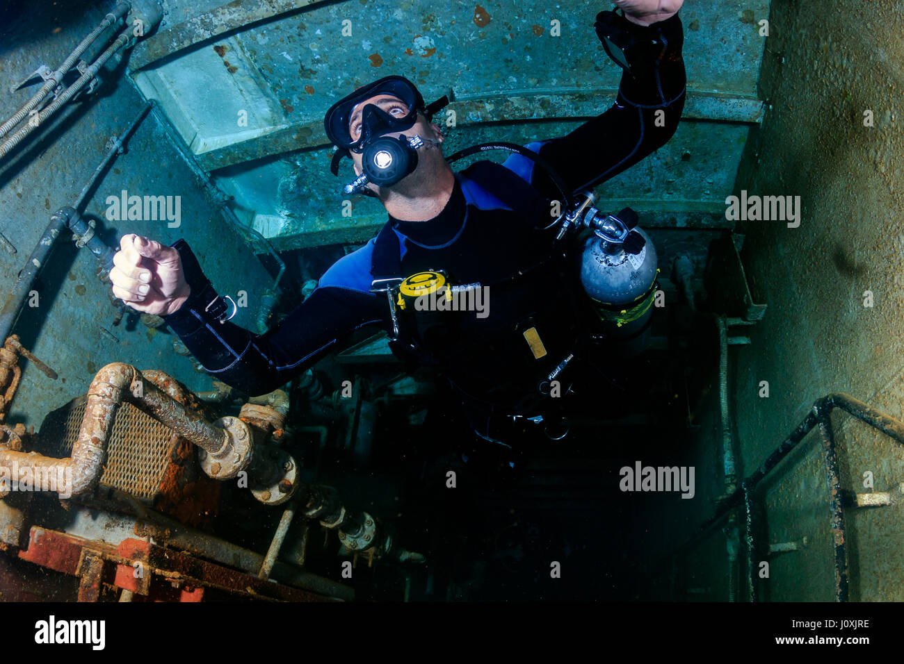 SCUBA diver in sidemount configuration deep inside an underwater shipwreck Stock Photo
