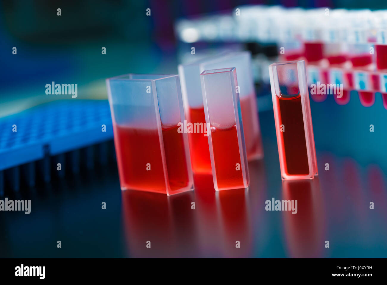 Quartz cuvette for laser chromatography with red liquid. Physical chemistry laboratory Stock Photo