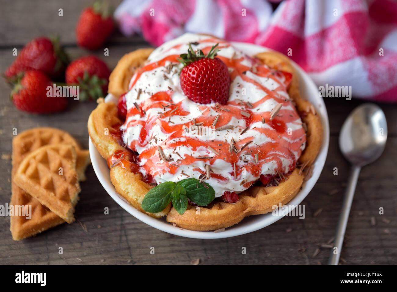 Golden waffle topped with fresh sliced strawberries and cream Stock ...