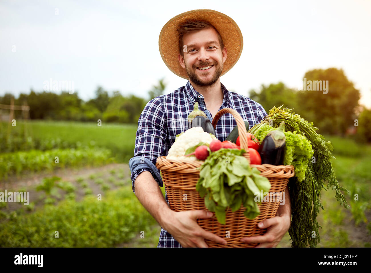 Nice young farmer with freshly picked vegetables in basket Stock Photo ...